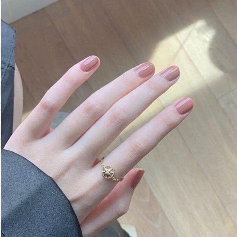 Close-up of a hand with manicured nails showcasing a soft pink shade, highlighting the use of Vaseline hand and nail cream