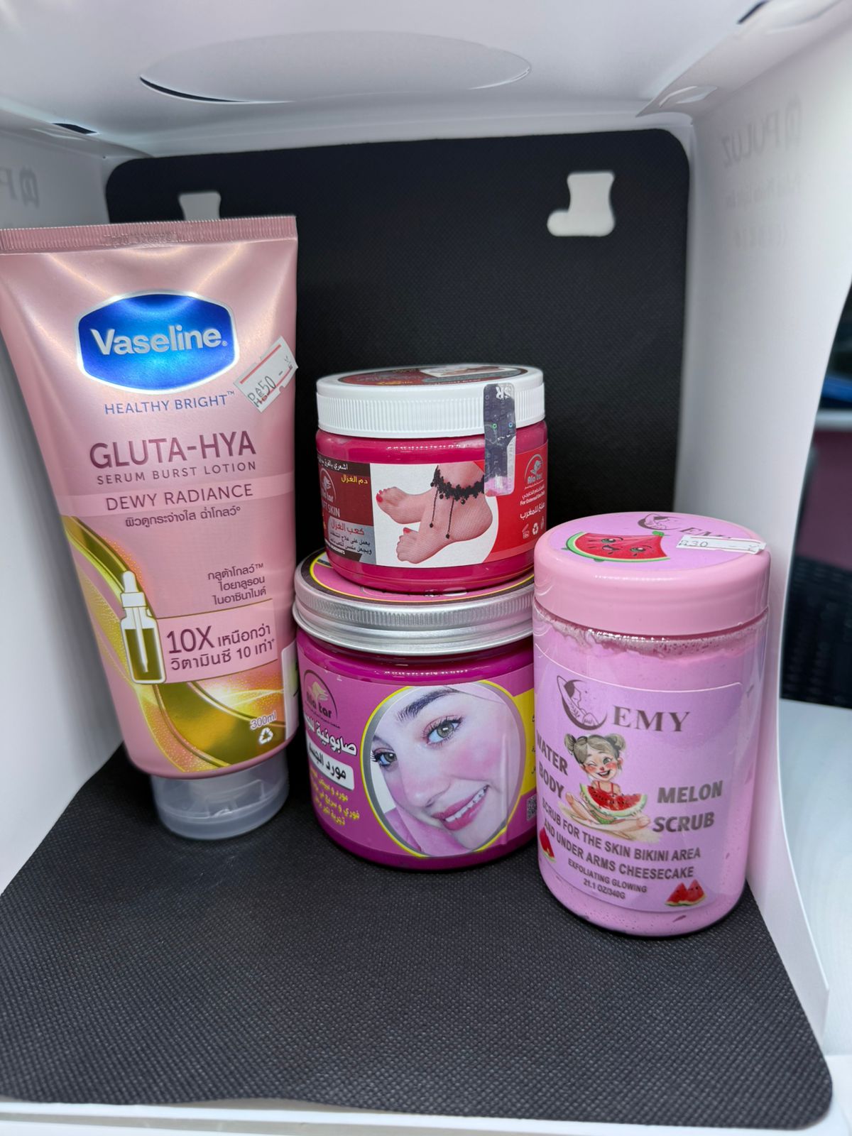 Collection of skincare products including Vaseline and Emtyーズ on a black mat.