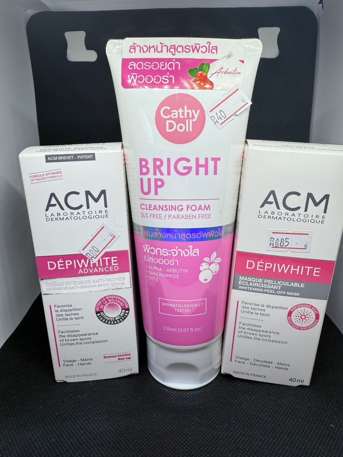 Cathy Doll Bright Up Cleansing Foam and ACM Depiwhite products on a black surface