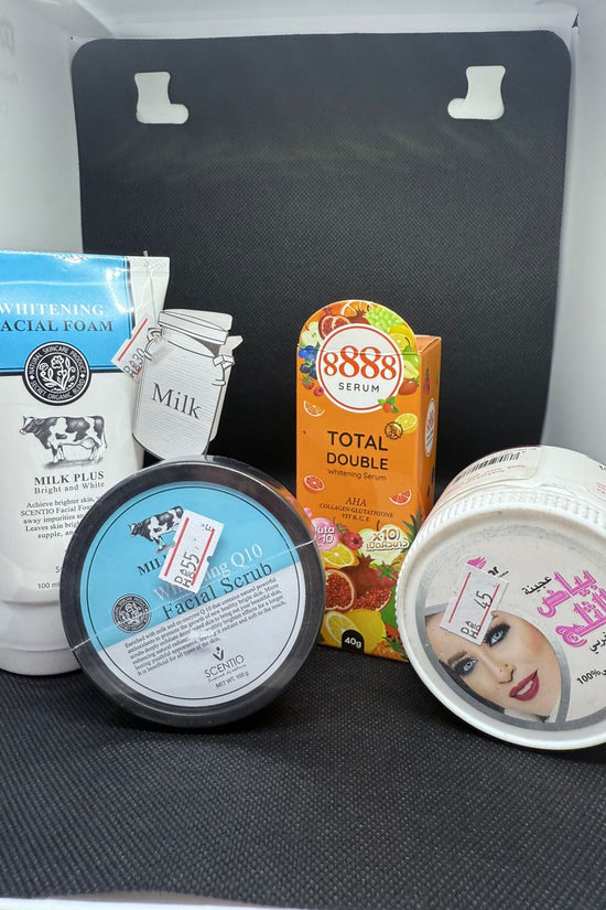 Assorted skincare products on a black surface with a white box in the background.