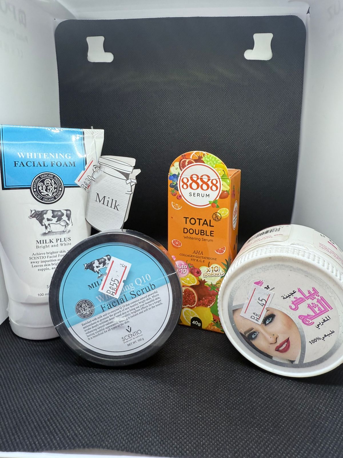 Assorted skincare products on a black surface with a white box in the background.