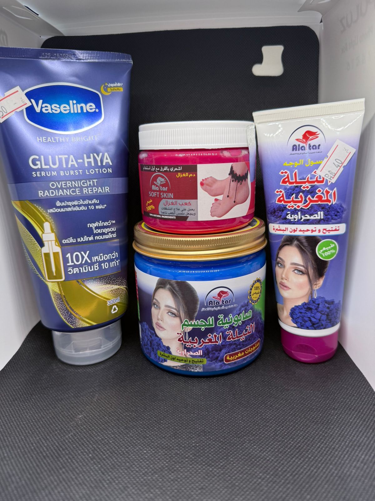 Collection of skincare products including Vaseline and Al Rehab on a gray surface.