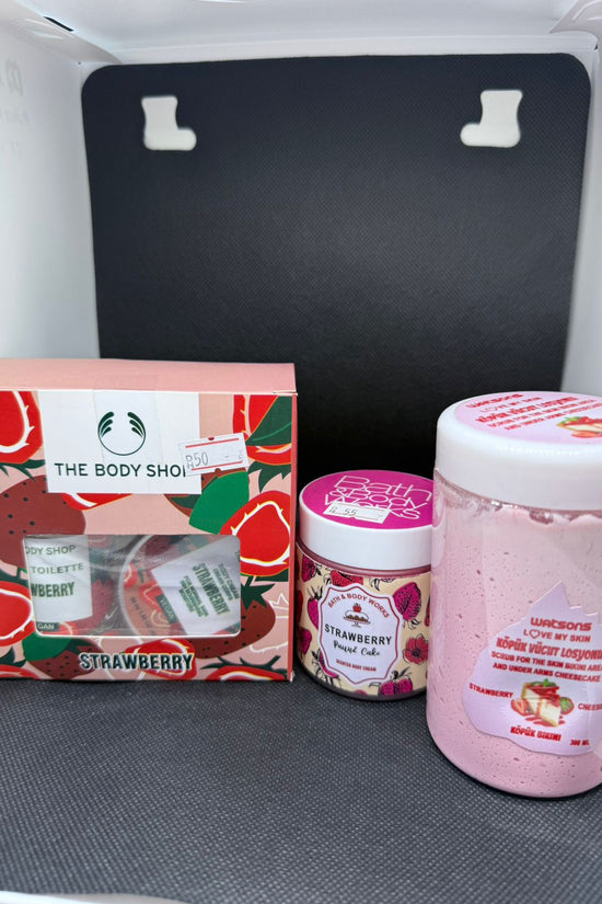 The Body Shop strawberry-themed products including a box, jar, and container on a gray surface.