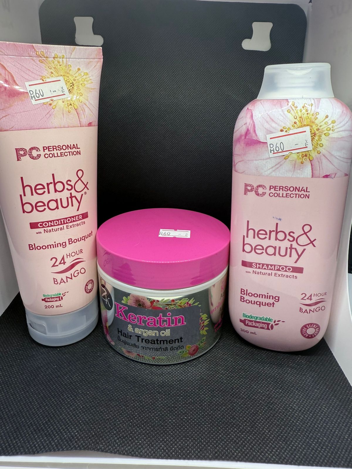 Herbs & Beauty hair care products including shampoo, conditioner, and hair treatment on a black surface.