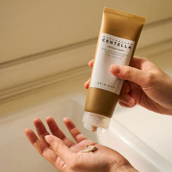 SKIN1004 Centella Ampoule Foam 125ml in a tube, shown dispensing foam onto a hand for skincare application